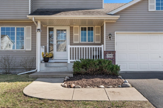 doorway to property with a porch, an attached garage, roof with shingles, and driveway