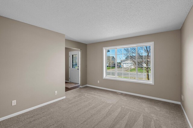 empty room with baseboards, carpet flooring, a textured ceiling, and visible vents