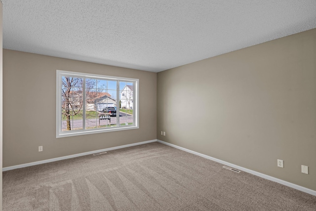 unfurnished room with baseboards, carpet flooring, a textured ceiling, and visible vents