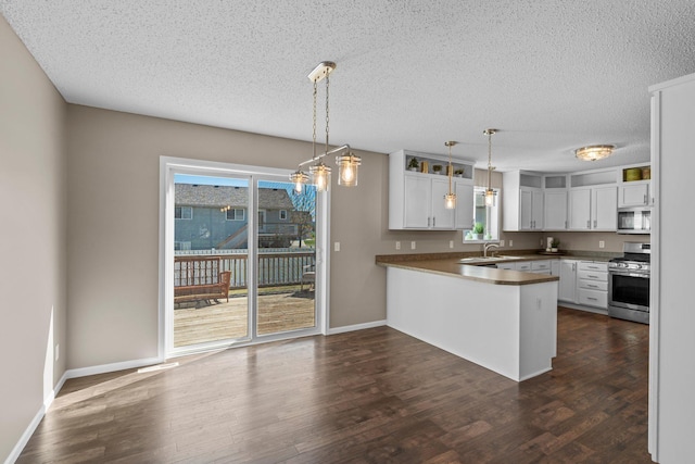 kitchen with appliances with stainless steel finishes, plenty of natural light, a peninsula, and a textured ceiling