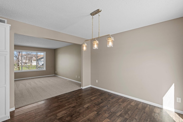unfurnished dining area with baseboards, dark wood-style flooring, and a textured ceiling