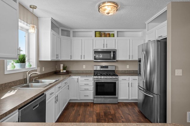 kitchen with a sink, a textured ceiling, appliances with stainless steel finishes, and white cabinets
