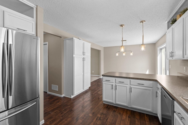 kitchen with visible vents, a peninsula, dark countertops, and stainless steel appliances