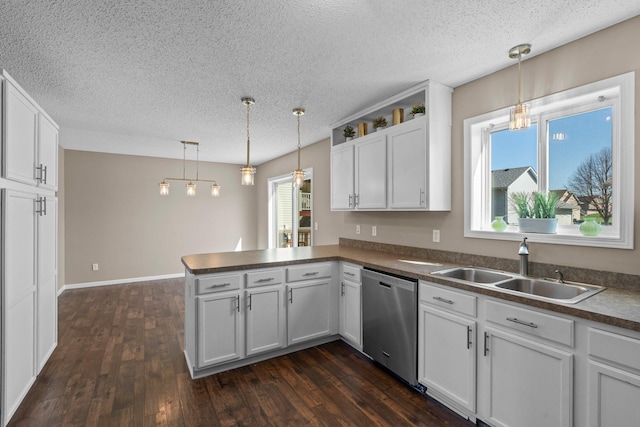 kitchen featuring a peninsula, a textured ceiling, a sink, and dishwasher
