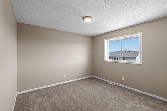 carpeted empty room featuring visible vents, a textured ceiling, and baseboards