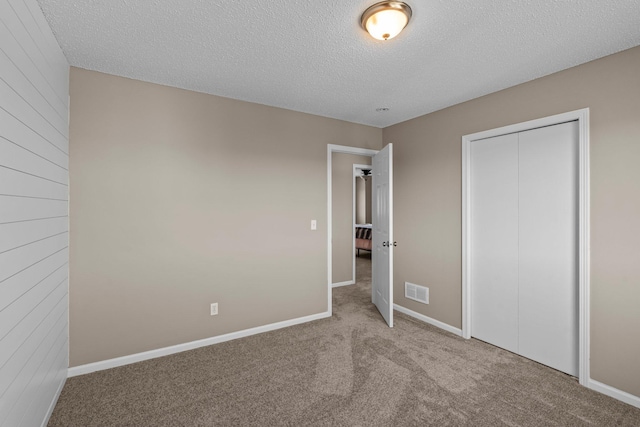 unfurnished bedroom with visible vents, a closet, baseboards, a textured ceiling, and carpet