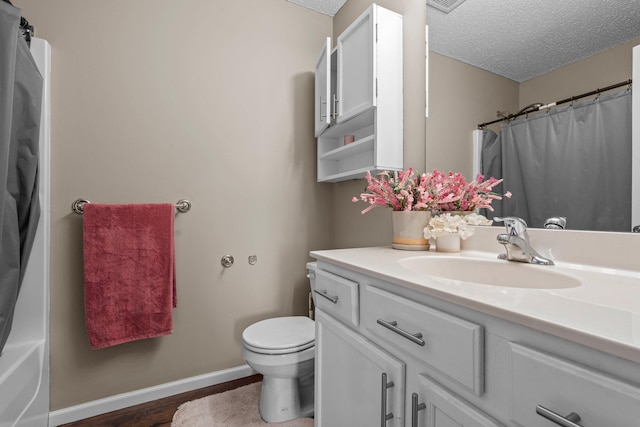 bathroom with vanity, wood finished floors, toilet, baseboards, and a textured ceiling