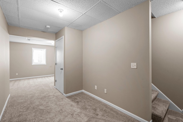hallway featuring carpet floors, stairs, a paneled ceiling, and baseboards