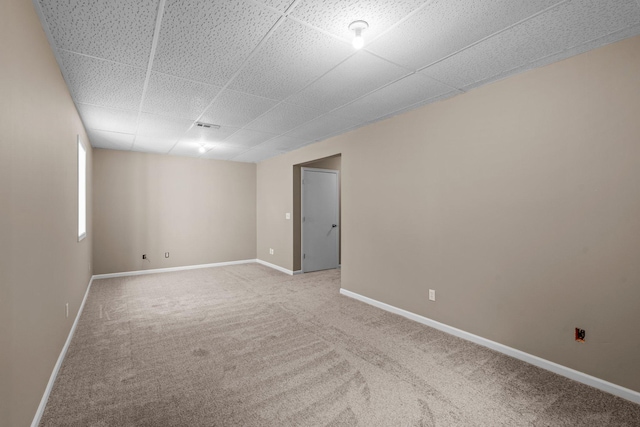 carpeted empty room with baseboards and a paneled ceiling