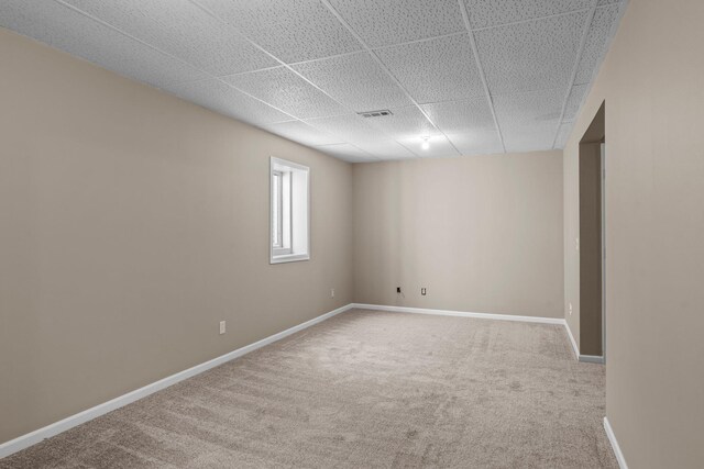 basement with carpet floors, a paneled ceiling, baseboards, and visible vents