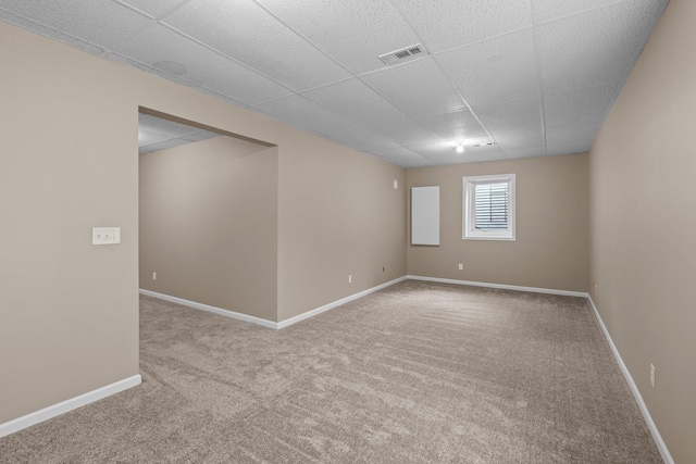 below grade area with carpet floors, baseboards, visible vents, and a drop ceiling