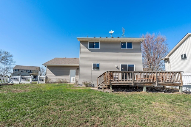 rear view of house with a lawn, a deck, and fence