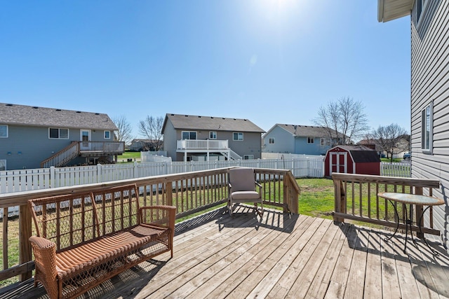 wooden terrace featuring a storage shed, a residential view, an outdoor structure, a fenced backyard, and a yard