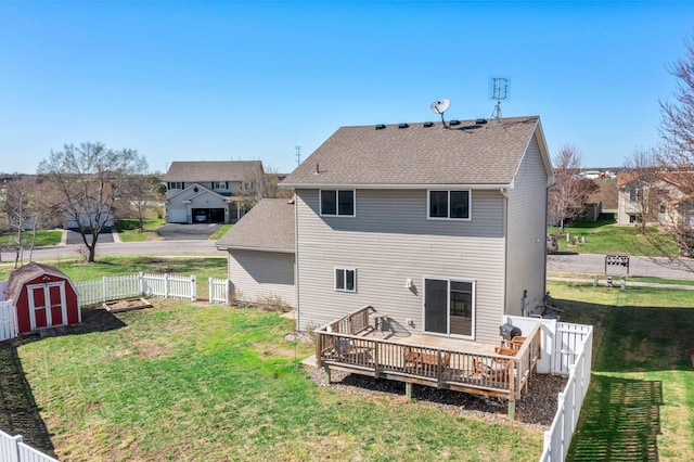 back of house featuring a storage unit, a fenced backyard, a lawn, and a wooden deck
