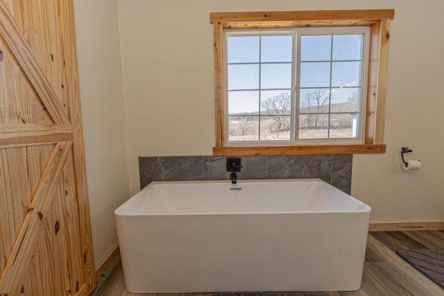 20462 Little Alps Rd NW, Evansville, MN 56326 - bathroom with baseboards, wood finished floors, and a freestanding bath