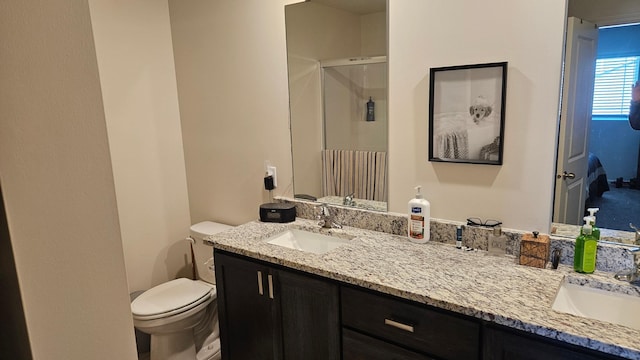 bathroom with double vanity, a stall shower, a sink, and toilet