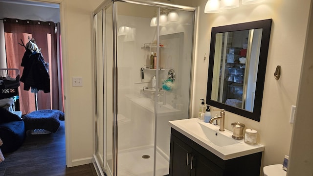 ensuite bathroom featuring ensuite bathroom, vanity, toilet, wood finished floors, and a stall shower