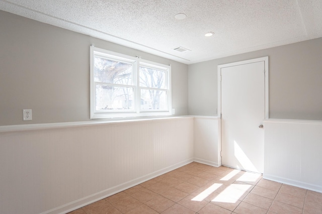 13100 Thomas Ave S, Burnsville, MN 55337 - unfurnished room featuring wainscoting, a textured ceiling, and light tile patterned floors