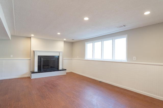 13100 Thomas Ave S, Burnsville, MN 55337 - unfurnished living room with a textured ceiling, wood finished floors, a tile fireplace, recessed lighting, and a wainscoted wall