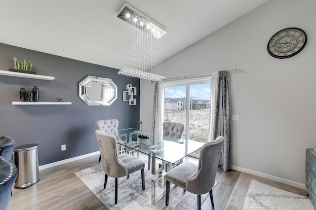 dining room featuring an inviting chandelier, wood finished floors, high vaulted ceiling, and baseboards