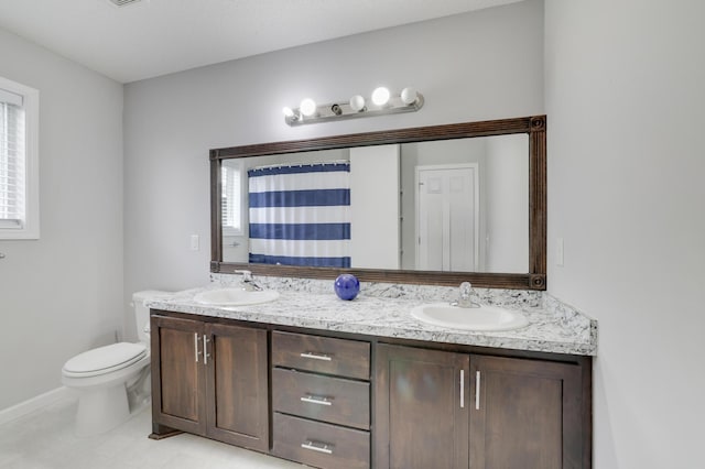 bathroom with double vanity, curtained shower, toilet, and a sink