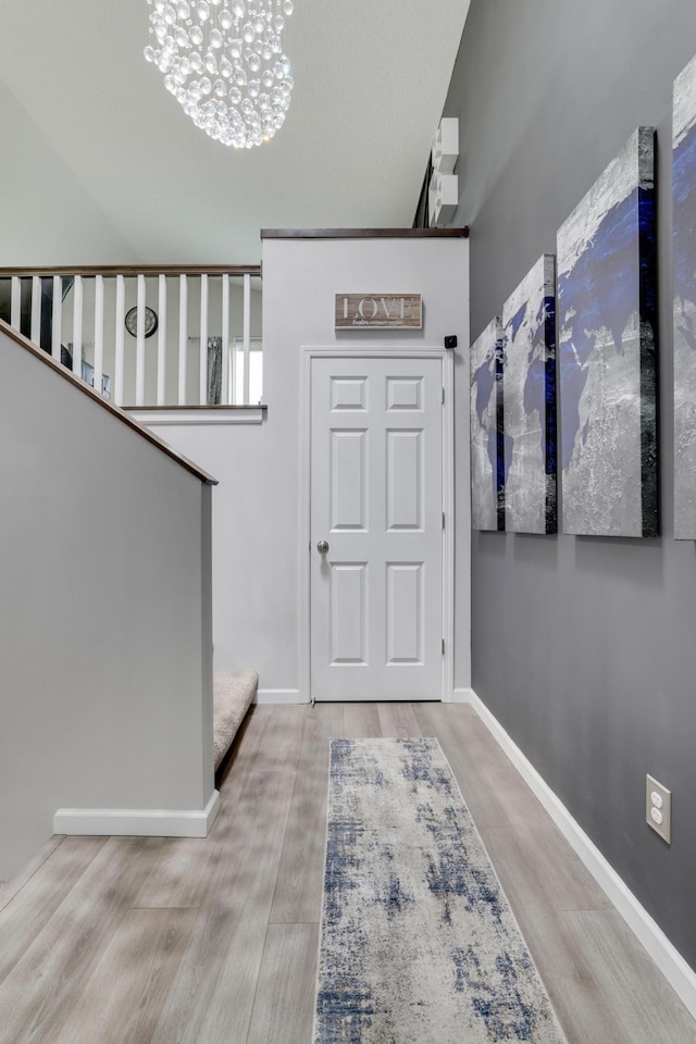 foyer with baseboards, wood finished floors, and an inviting chandelier