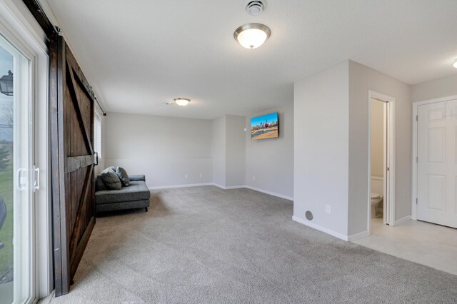 living area featuring a barn door, light carpet, and baseboards