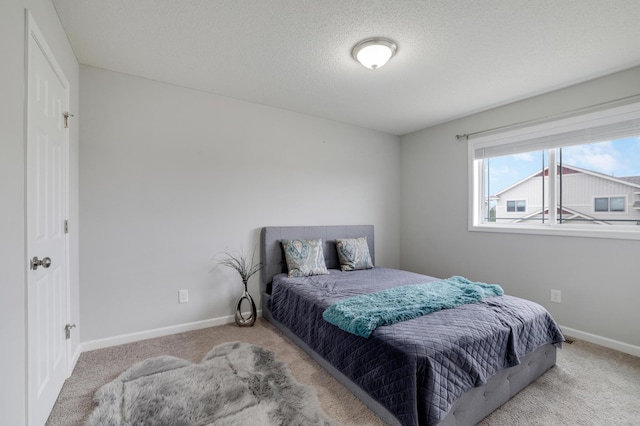 carpeted bedroom featuring a textured ceiling and baseboards