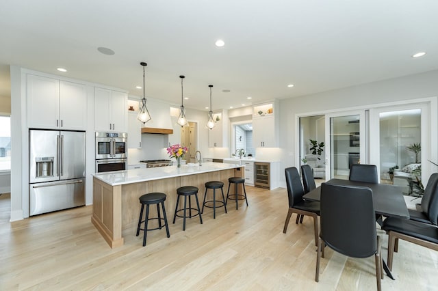 3251 Century Ridge Pl NE, Rochester, MN 55906 - kitchen with appliances with stainless steel finishes, wine cooler, a kitchen breakfast bar, light countertops, and light wood-style floors