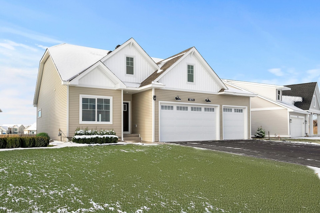 modern farmhouse featuring board and batten siding, a garage, a front yard, and aphalt driveway