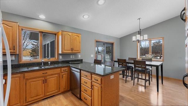 kitchen featuring stainless steel dishwasher, a peninsula, lofted ceiling, light wood-style floors, and a sink