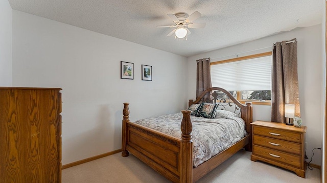bedroom featuring baseboards, a textured ceiling, light colored carpet, and ceiling fan