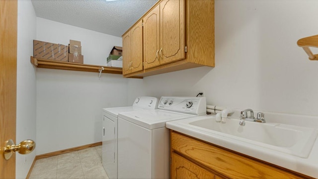 laundry area with cabinet space, a sink, separate washer and dryer, a textured ceiling, and baseboards