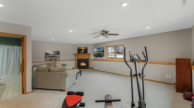 exercise room featuring recessed lighting, a lit fireplace, ceiling fan, and light carpet
