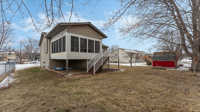 back of property with fence, a sunroom, stairs, a storage unit, and a yard