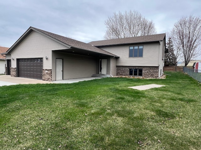 view of front facade featuring driveway, a front yard, brick siding, fence, and an attached garage