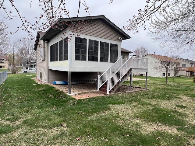 rear view of house featuring a yard, a deck, stairs, and a sunroom