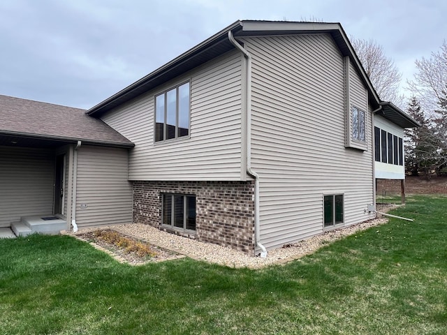 view of side of home with a lawn and brick siding