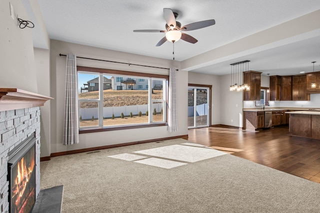 27290 Petes Hill Trl, Elko New Market, MN 55020 - unfurnished living room with dark wood-style flooring, baseboards, a ceiling fan, a fireplace with flush hearth, and a sink