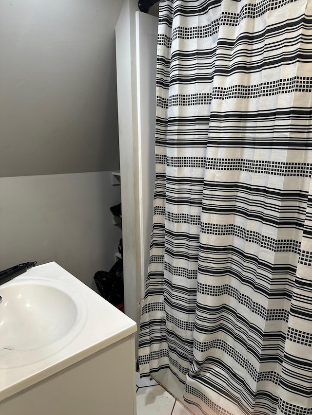 bathroom featuring curtained shower, vaulted ceiling, tile patterned flooring, and vanity