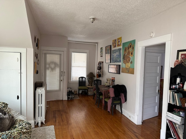 interior space featuring a textured ceiling, radiator heating unit, and hardwood / wood-style flooring