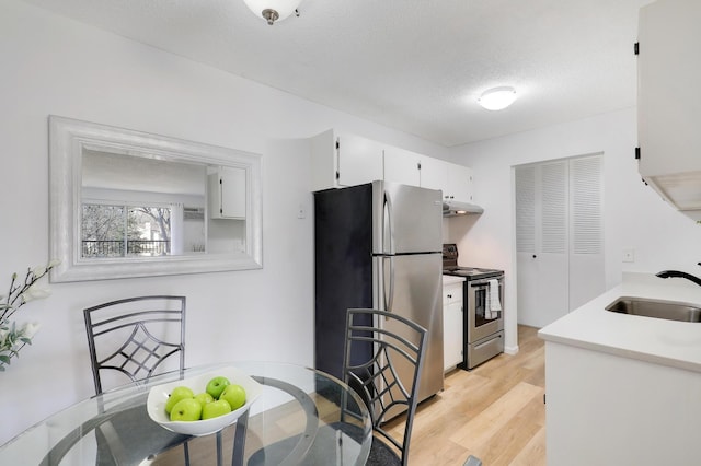 2800 Hillsboro Ave N Unit 220, New Hope, MN 55427 - kitchen featuring appliances with stainless steel finishes, under cabinet range hood, white cabinetry, light wood-style flooring, and light countertops