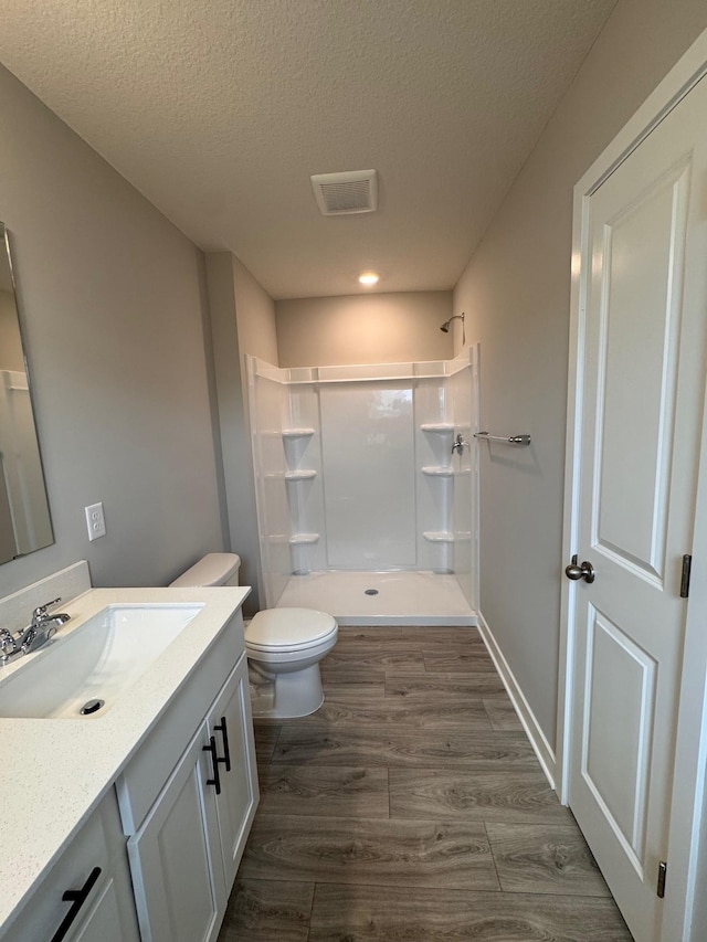 9829 89th St S, Cottage Grove, MN 55016 - bathroom with a stall shower, a textured ceiling, vanity, wood finished floors, and toilet