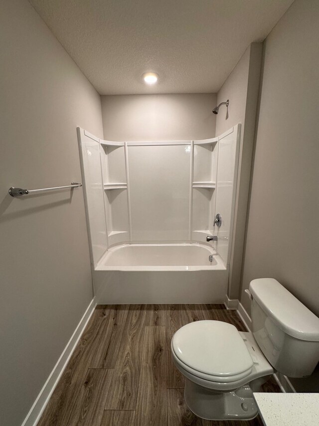 9829 89th St S, Cottage Grove, MN 55016 - bathroom with toilet, wood finished floors, washtub / shower combination, baseboards, and a textured ceiling