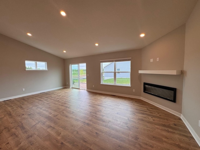 9829 89th St S, Cottage Grove, MN 55016 - unfurnished living room with dark wood-type flooring, lofted ceiling, a glass covered fireplace, recessed lighting, and baseboards