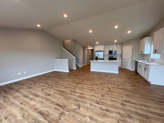 9829 89th St S, Cottage Grove, MN 55016 - kitchen featuring a sink, vaulted ceiling, stainless steel appliances, open floor plan, and tasteful backsplash