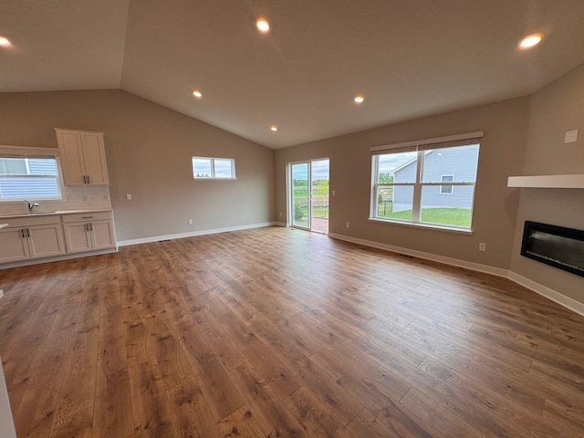 9829 89th St S, Cottage Grove, MN 55016 - unfurnished living room featuring wood finished floors, lofted ceiling, a fireplace, recessed lighting, and baseboards