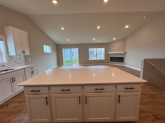 9829 89th St S, Cottage Grove, MN 55016 - kitchen featuring dark wood-style flooring, lofted ceiling, white cabinetry, backsplash, and a sink