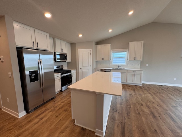 9829 89th St S, Cottage Grove, MN 55016 - kitchen featuring appliances with stainless steel finishes, a sink, white cabinets, decorative backsplash, and lofted ceiling