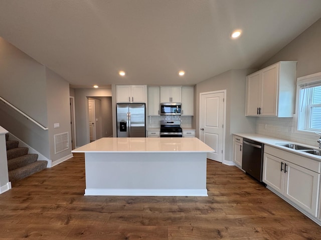 9829 89th St S, Cottage Grove, MN 55016 - kitchen featuring stainless steel appliances, a sink, a kitchen island, tasteful backsplash, and white cabinetry